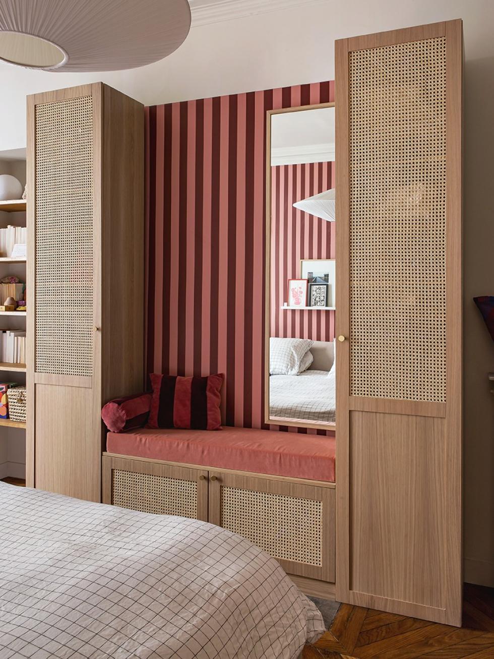 Das Schlafzimmer von Lisa Gachet, mit bordeauxroter und rosafarbener Tapete, und einem Kleiderschrank aus Flechtdesign und Eiche Natur.