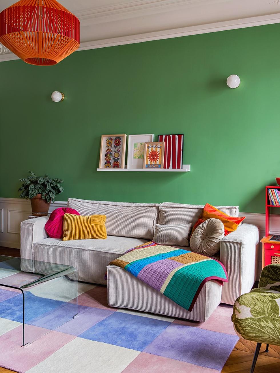 Le salon coloré de Lisa Gachet : mur vert, tapis violet, canapé en velours côtelé.