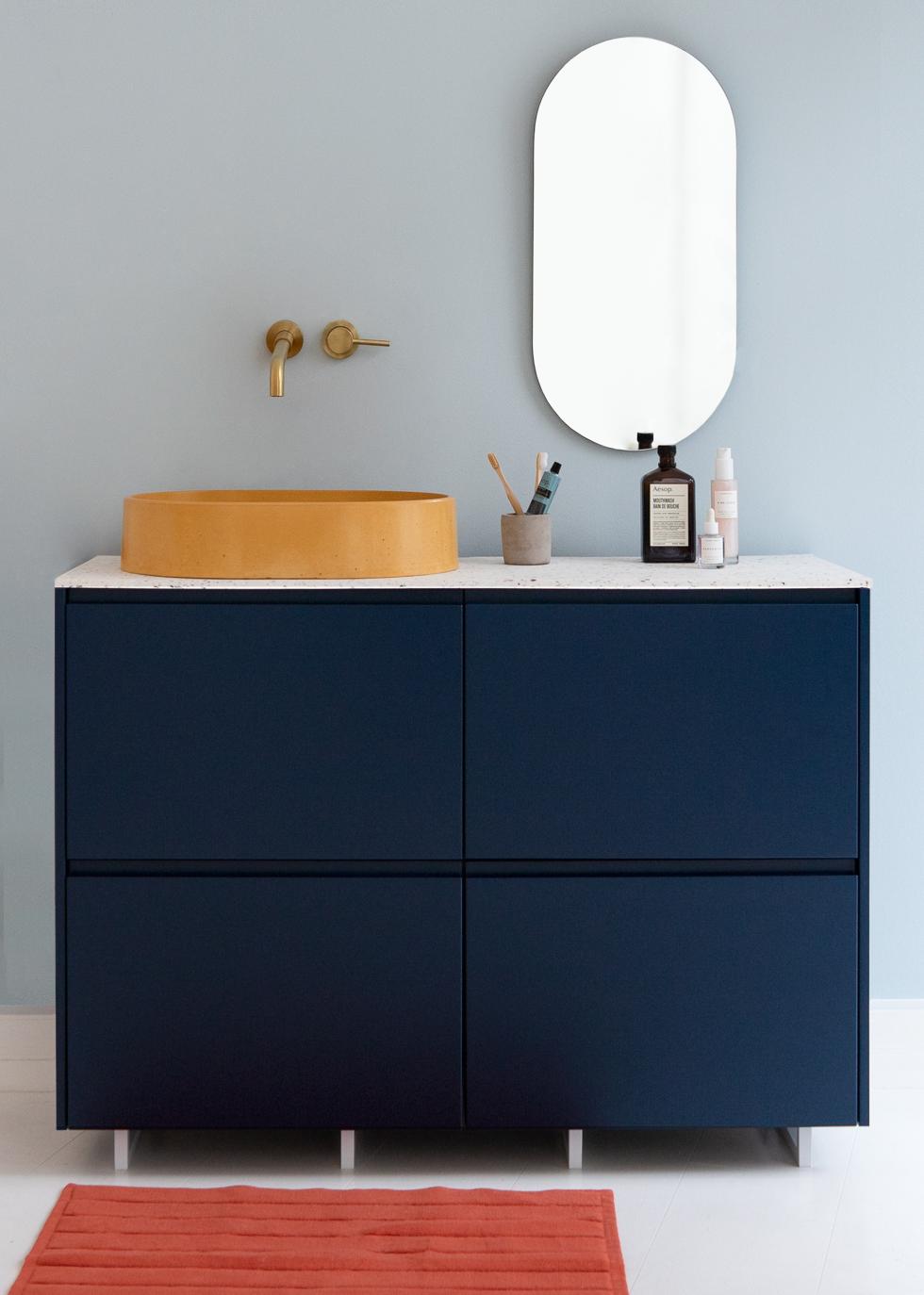 Midnight blue floor-standing bathroom cabinet with U-shaped fronts, yellow washbasin.