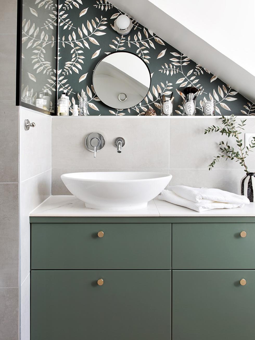 Salle de bain verte avec détails en laiton et papier peint au mur