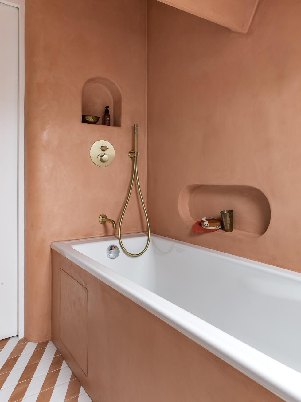 Salle de bain avec baignoire, murs en bétons ciré et robinetterie en laiton.